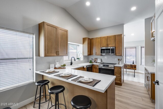 2730 E Desert Trumpet Rd, Phoenix, AZ 85048 - kitchen featuring appliances with stainless steel finishes, a sink, a peninsula, vaulted ceiling, and brown cabinetry