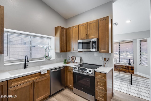 2730 E Desert Trumpet Rd, Phoenix, AZ 85048 - kitchen with stainless steel appliances, a sink, backsplash, brown cabinetry, and light countertops