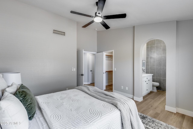 2730 E Desert Trumpet Rd, Phoenix, AZ 85048 - bedroom featuring arched walkways, light wood finished floors, a walk in closet, connected bathroom, and baseboards