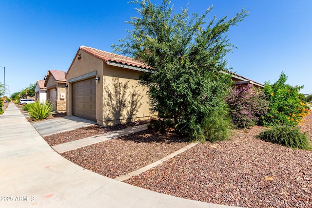 14233 W Georgia Dr, Surprise, AZ 85379 - view of home's exterior featuring a tile roof, stucco siding, a garage, and driveway