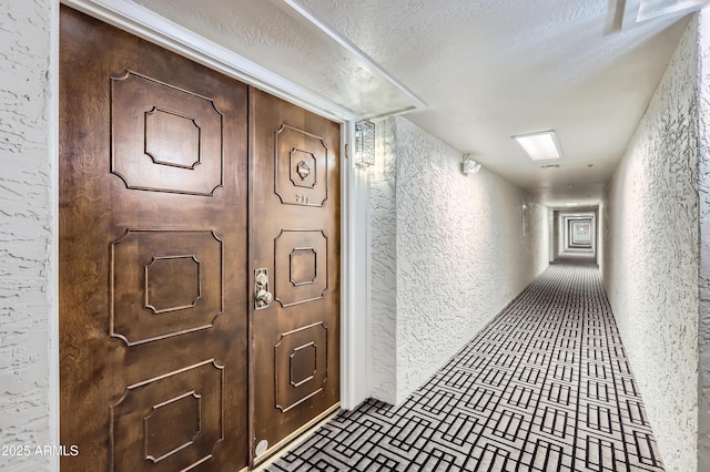 hall featuring brick floor, a textured wall, and a textured ceiling