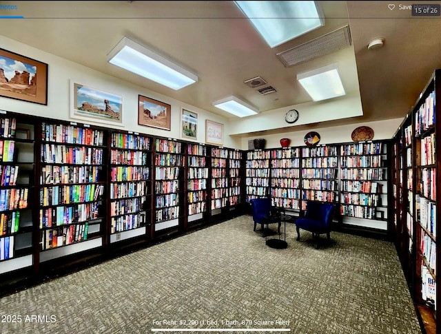 sitting room with carpet and wall of books