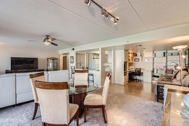 dining room featuring a textured ceiling, wood finished floors, a ceiling fan, and track lighting