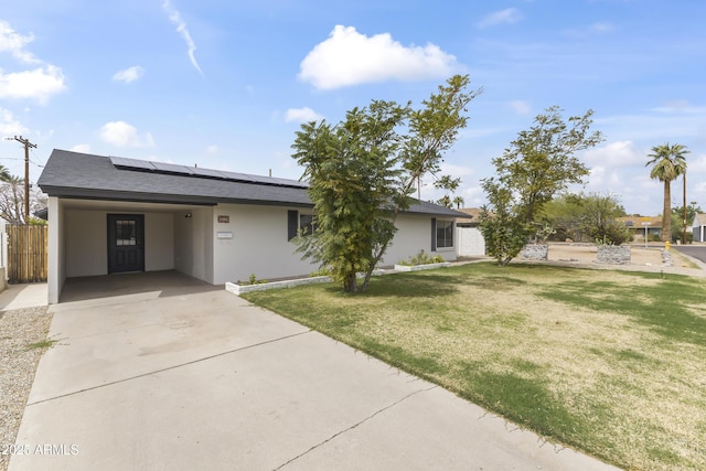 ranch-style home featuring driveway, roof mounted solar panels, a front lawn, a carport, and stucco siding