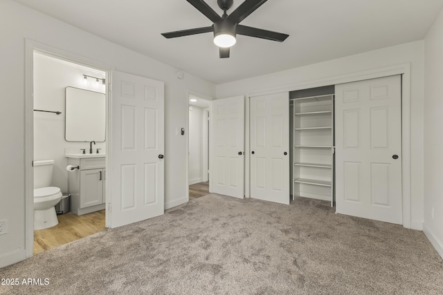 unfurnished bedroom featuring carpet, a closet, ensuite bathroom, a sink, and baseboards