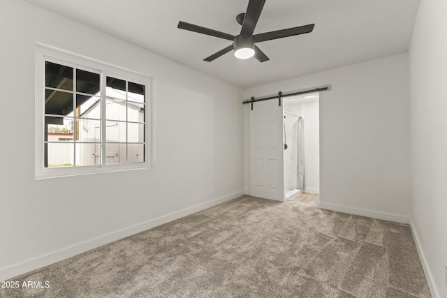 interior space with a barn door, baseboards, and a ceiling fan