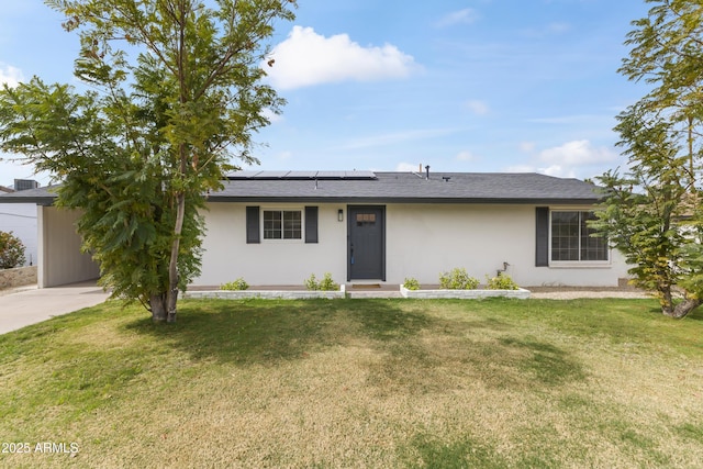 ranch-style home featuring a shingled roof, stucco siding, a front yard, and roof mounted solar panels