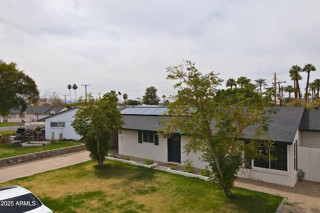 view of front of house featuring a front lawn, a shingled roof, and stucco siding