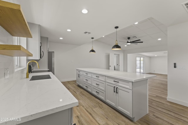 kitchen with pendant lighting, baseboards, a sink, and light wood-style floors