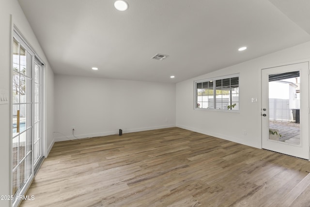 unfurnished room featuring recessed lighting, visible vents, light wood-style floors, vaulted ceiling, and baseboards