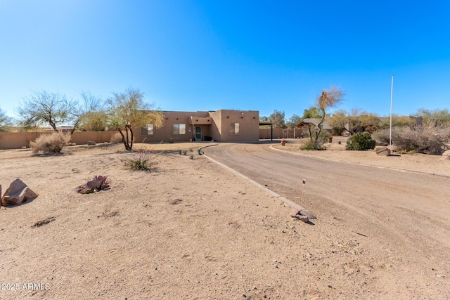 pueblo revival-style home featuring fence and stucco siding