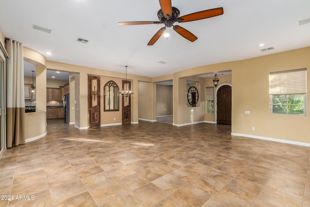 unfurnished living room featuring ceiling fan with notable chandelier