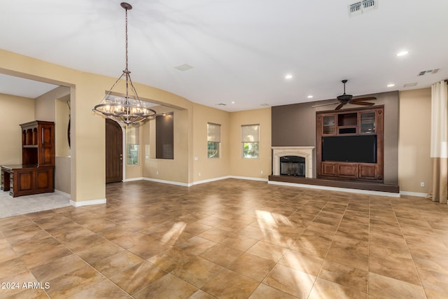 unfurnished living room featuring ceiling fan with notable chandelier