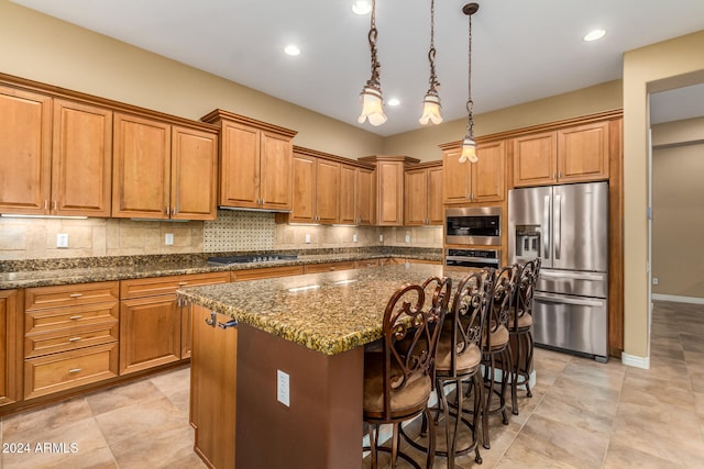 kitchen featuring dark stone countertops, hanging light fixtures, a kitchen island, and appliances with stainless steel finishes