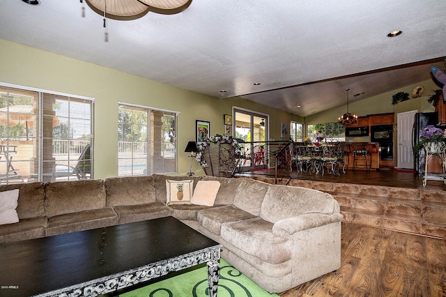 living room with a textured ceiling, wood-type flooring, and vaulted ceiling