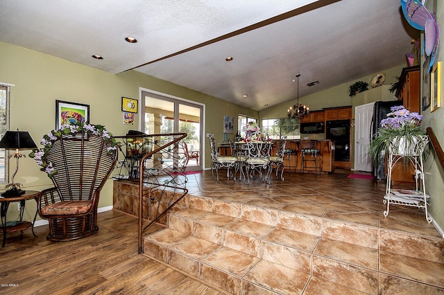 dining area with lofted ceiling, hardwood / wood-style floors, and a notable chandelier