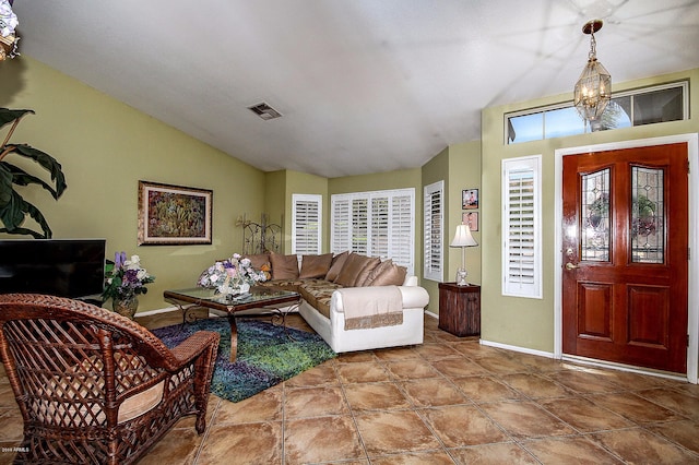 tiled entryway with lofted ceiling and an inviting chandelier