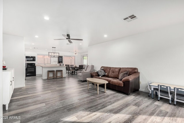 living room with wood-type flooring and ceiling fan with notable chandelier