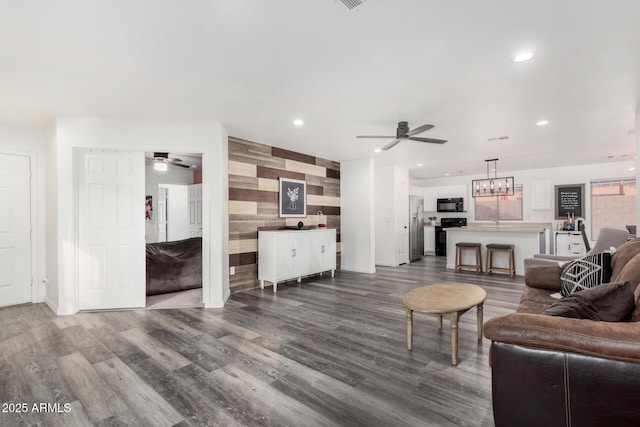 living room featuring ceiling fan, sink, hardwood / wood-style floors, and wooden walls