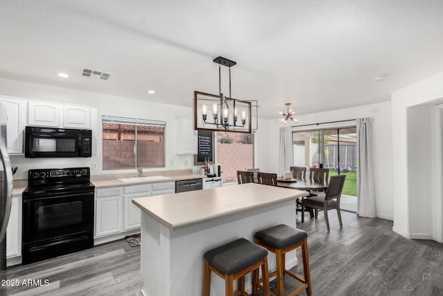 kitchen featuring sink, wood-type flooring, black appliances, white cabinets, and a kitchen island