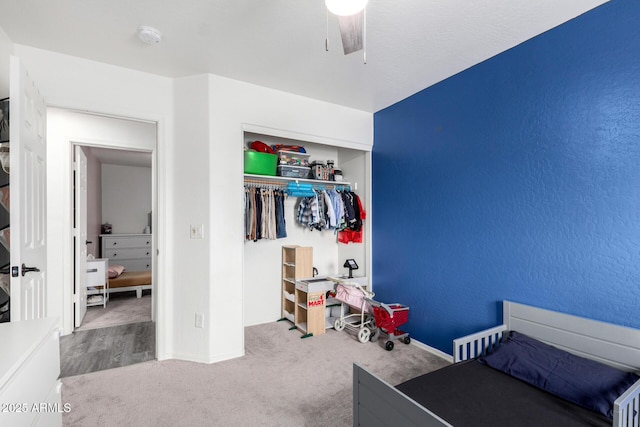 bedroom with light colored carpet, ceiling fan, and a closet