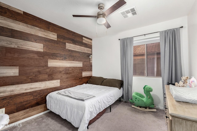 bedroom featuring carpet flooring, ceiling fan, and wood walls