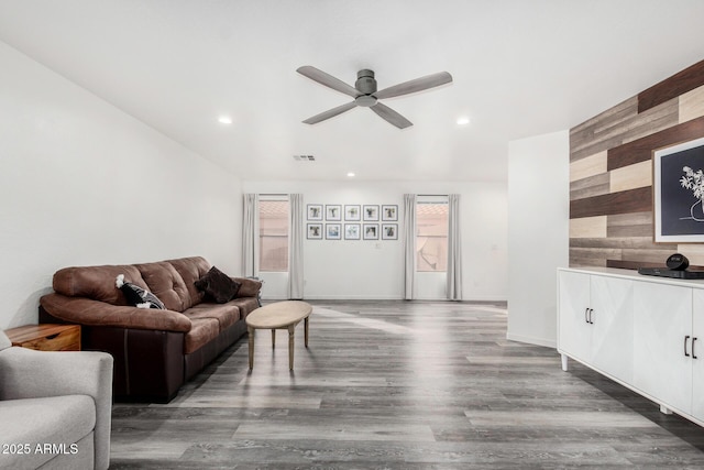 living room with hardwood / wood-style floors, ceiling fan, and wood walls