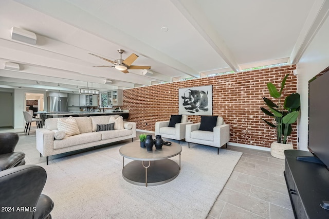 living room featuring brick wall, beamed ceiling, sink, and ceiling fan