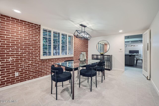 dining space with an inviting chandelier and brick wall