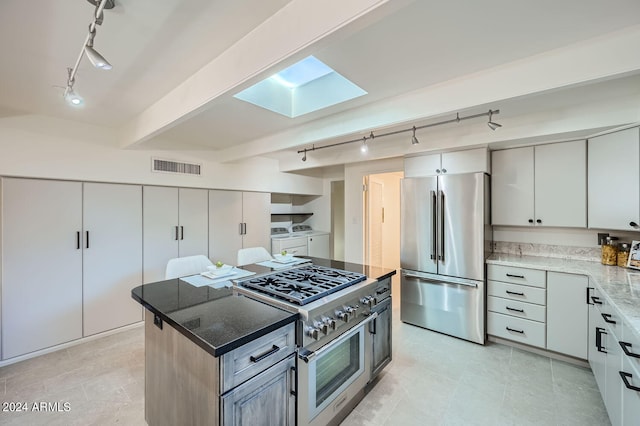 kitchen featuring a skylight, beam ceiling, track lighting, washer and clothes dryer, and stainless steel appliances