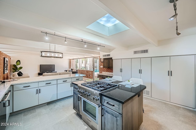 kitchen featuring a skylight, beam ceiling, track lighting, a center island, and double oven range