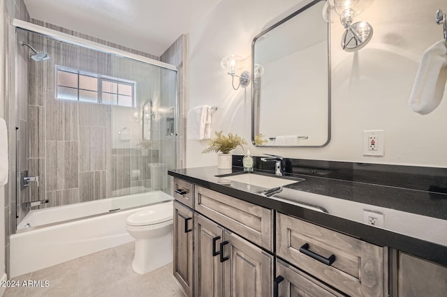 full bathroom with tile patterned flooring, bath / shower combo with glass door, vanity, and toilet