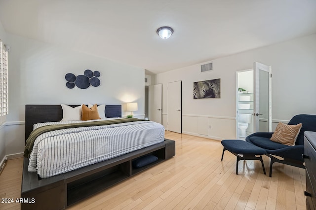 bedroom with light wood-type flooring and ensuite bathroom