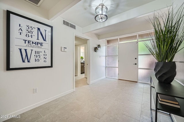 foyer entrance featuring beam ceiling and a chandelier