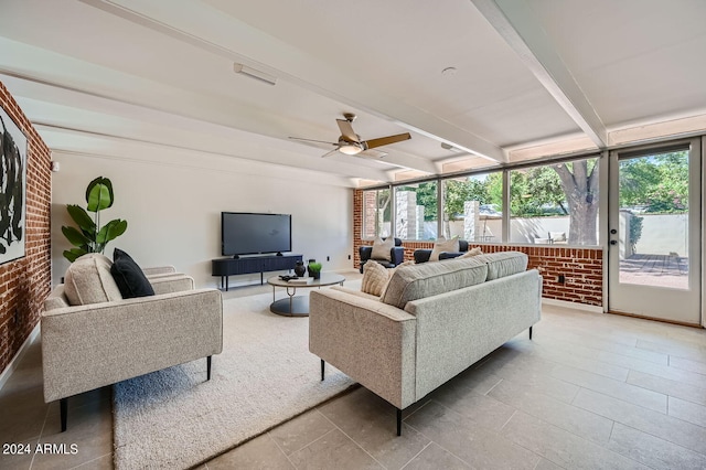 living room featuring beam ceiling, ceiling fan, and brick wall