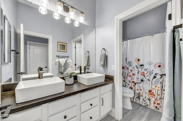 full bath with toilet, double vanity, wood finished floors, and curtained shower