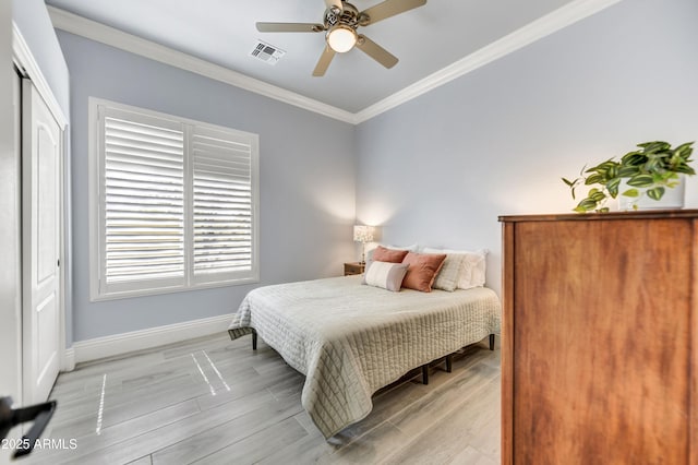 bedroom featuring crown molding, baseboards, light wood-style floors, a ceiling fan, and a closet