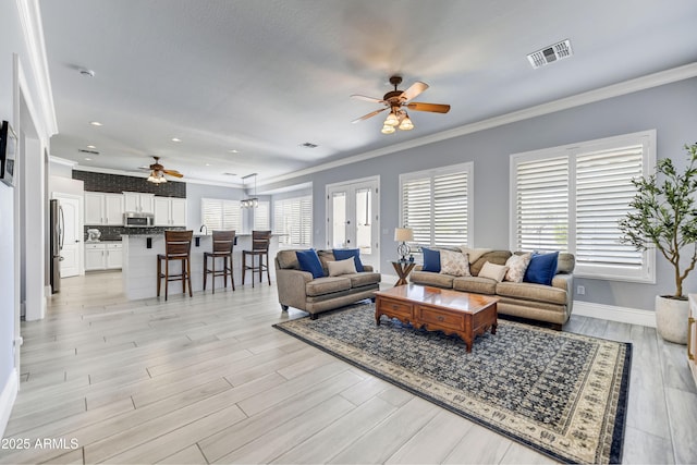 living area featuring ceiling fan, crown molding, baseboards, light wood-type flooring, and recessed lighting