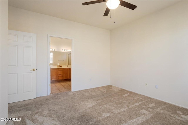 unfurnished bedroom featuring ensuite bathroom, light colored carpet, and ceiling fan