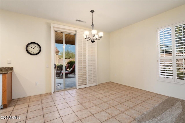 unfurnished dining area featuring an inviting chandelier and light tile patterned flooring