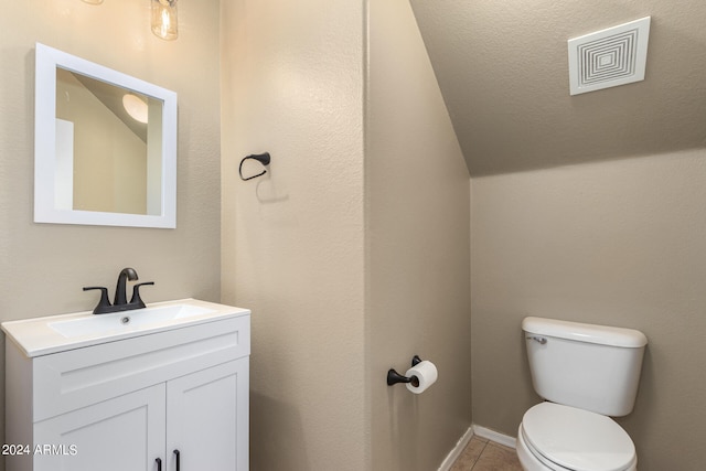 bathroom with a textured ceiling, vanity, toilet, and tile patterned floors