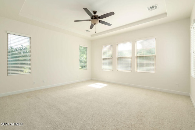 carpeted spare room with ceiling fan and a raised ceiling