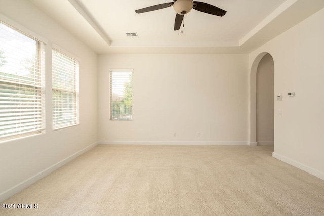 carpeted empty room with a tray ceiling and ceiling fan