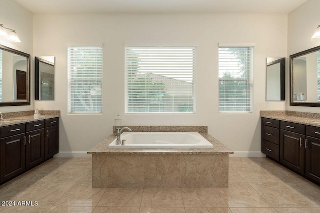 bathroom with tiled bath, vanity, and tile patterned floors