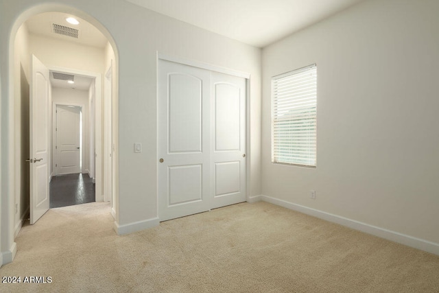 unfurnished bedroom with light carpet and a closet