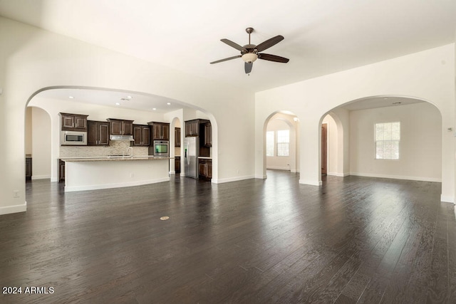 unfurnished living room featuring dark hardwood / wood-style flooring, ceiling fan, sink, and a wealth of natural light