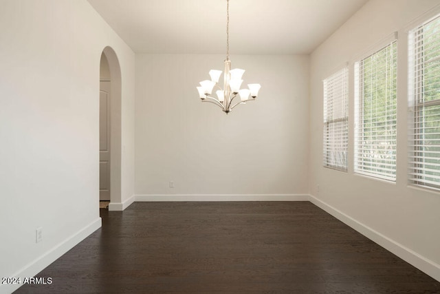 unfurnished room featuring dark hardwood / wood-style floors, a chandelier, and a healthy amount of sunlight