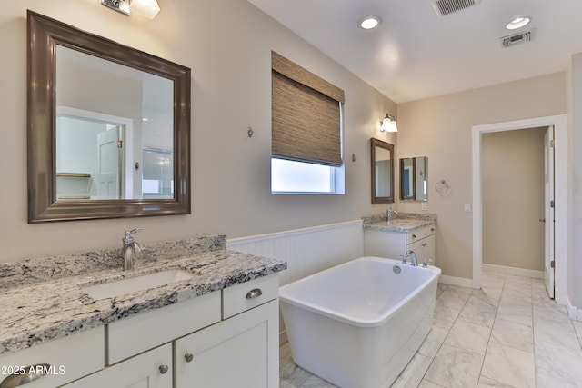 1505 W Orangewood Ave W, Phoenix, AZ 85021 - full bathroom with marble look tiles, a soaking tub, two vanities, a wainscoted wall, and recessed lighting