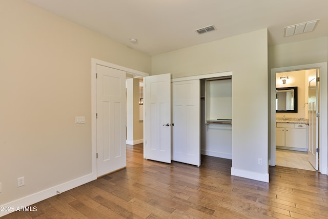 1505 W Orangewood Ave W, Phoenix, AZ 85021 - unfurnished bedroom featuring wood finished floors, a closet, and ensuite bath