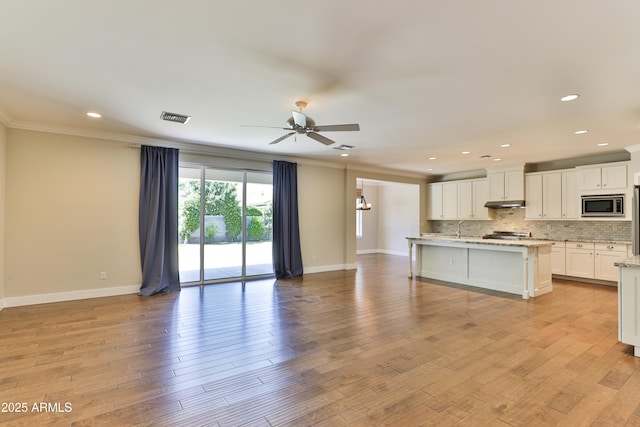 1505 W Orangewood Ave W, Phoenix, AZ 85021 - kitchen with stainless steel microwave, open floor plan, ceiling fan, crown molding, and decorative backsplash